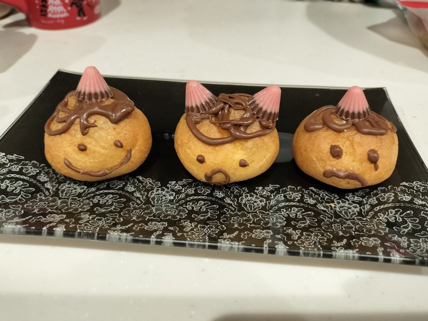 黒か茶色のチョコペンで顔を自由に書く。髪の毛はぐるぐると適当でOK。固まる前にアポロをのせる（1本でも2本でも）