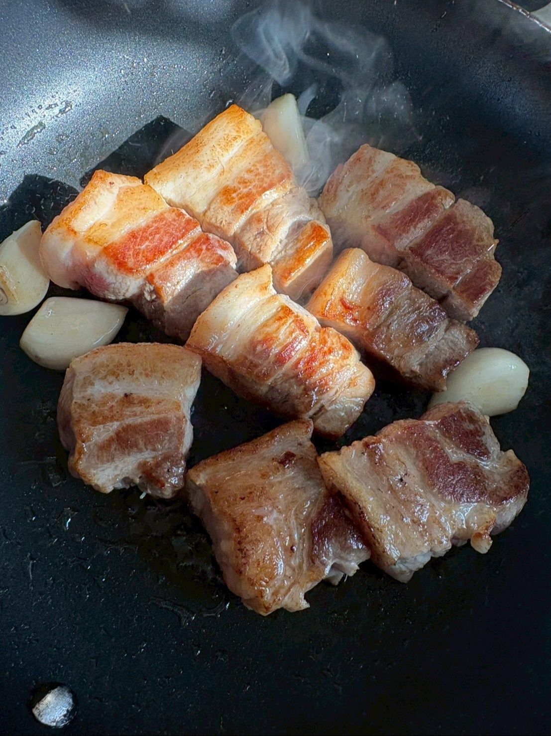 フライパンにバラ肉の塊とニンニクを入れてしっかり焼き目を付けます。
