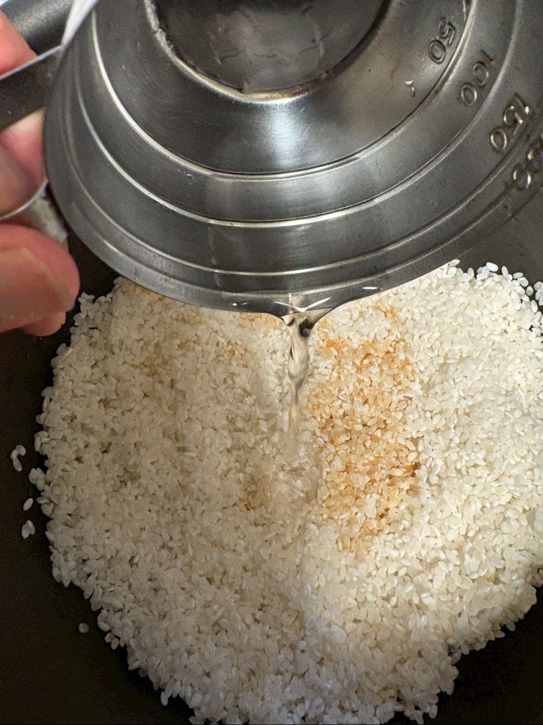 炊飯器に研いだ米を入れて、煮汁を加え、日本酒をたっぷり加える