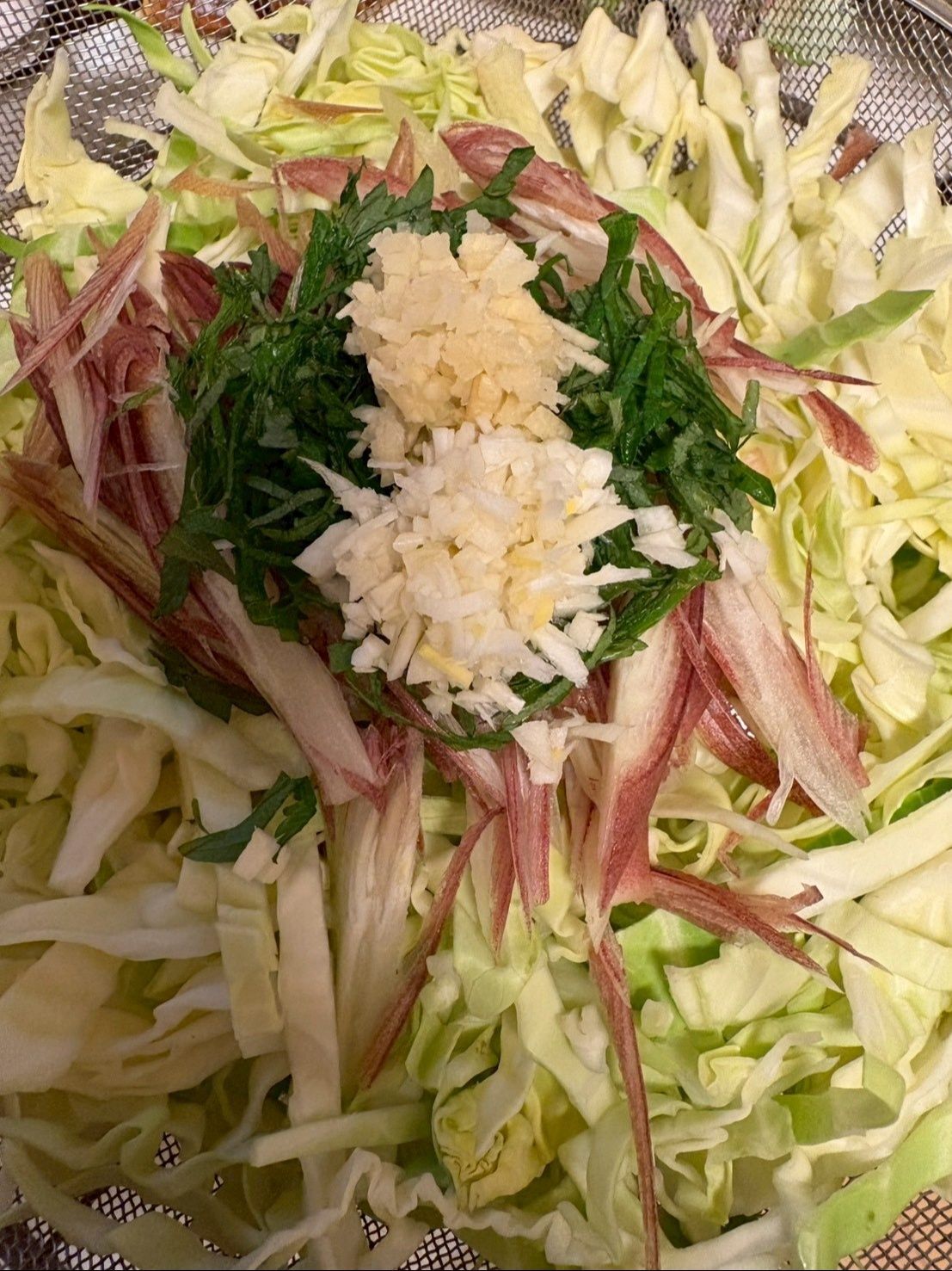 キャベツの上にミョウガ、大葉、生姜、ニンニクの順番で乗せます