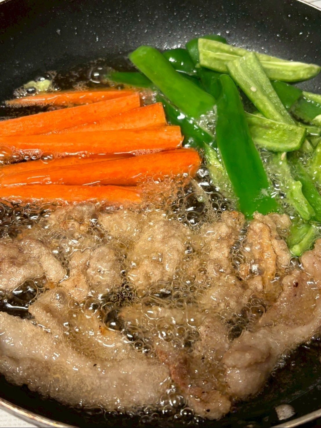 お肉をカラッと揚げたら人参とピーマンも素揚げにします。