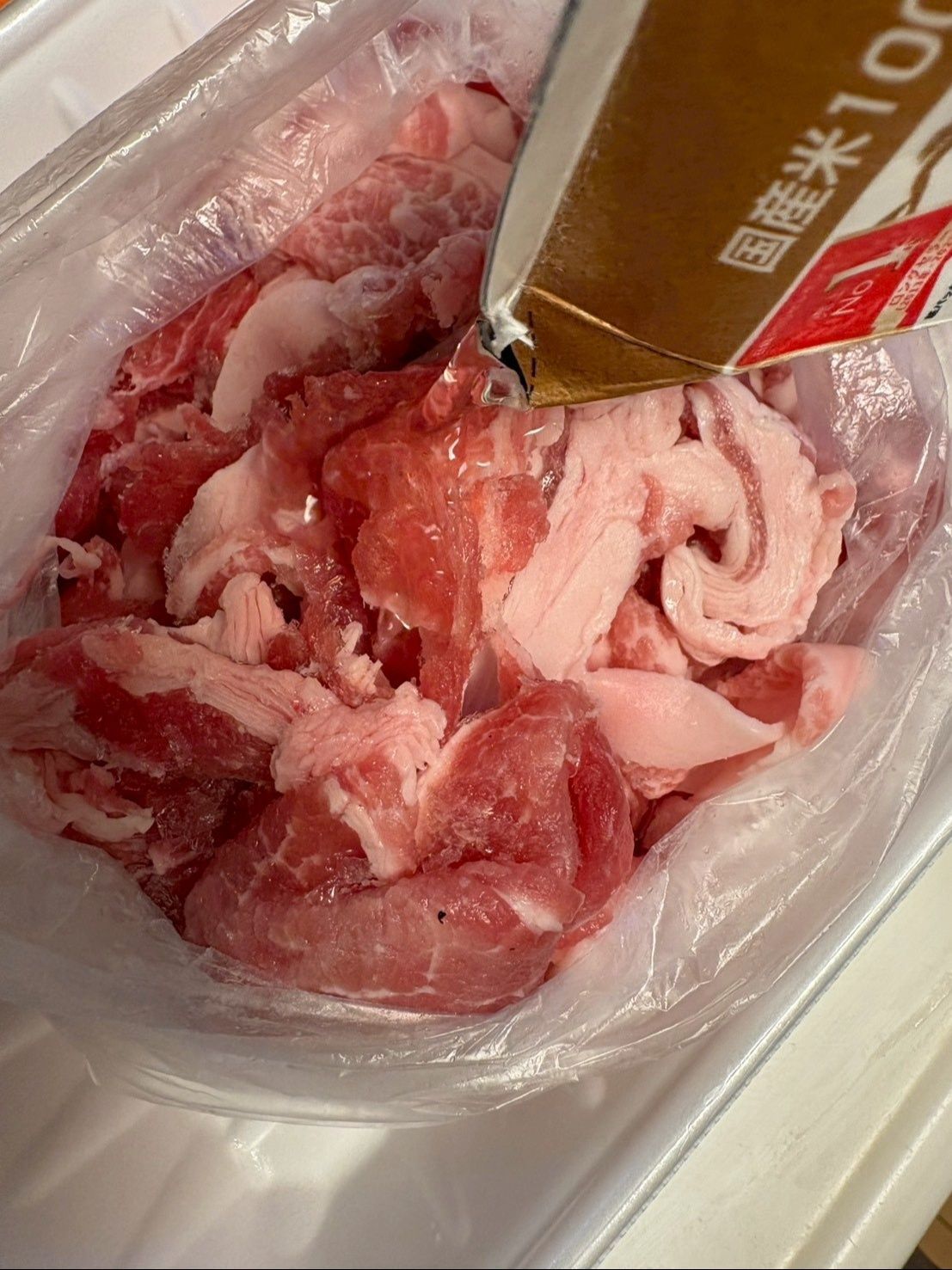 ビニール袋に豚コマを入れて日本酒をかけます。