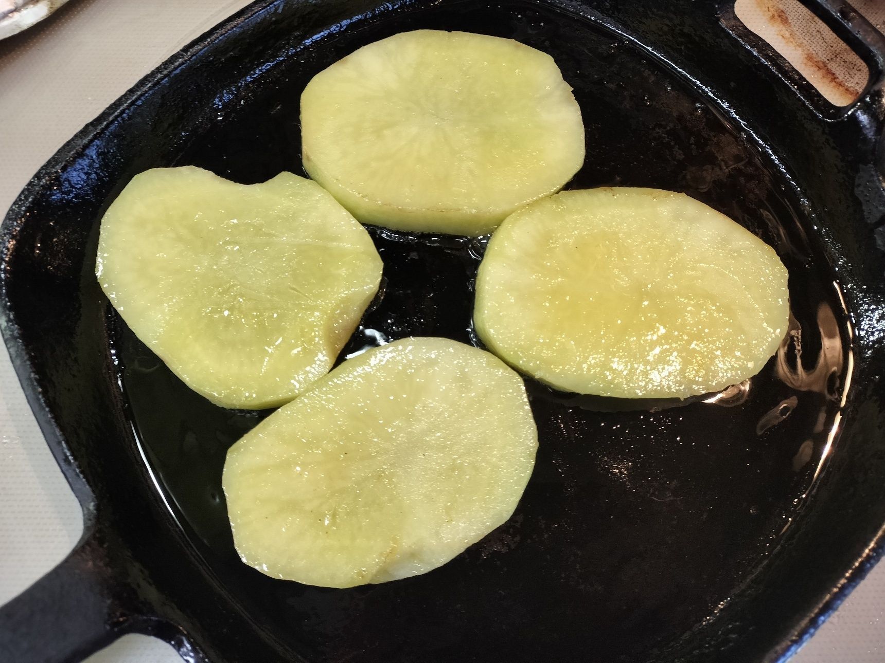 3、鉄フライパンに、オリーブを入れる→じゃがいもを入れて焼く（中まで火が通り表面がこんがり焼けるまで）→厚切りベーコンを加えて両面を焼く→じゃがいもに、マヨネーズ・とろけるチーズ・香味香るスパイス塩をかける→ひっくり返してチーズを溶かす→チーズが溶けたら、ひっくり返す→人参の葉を添える