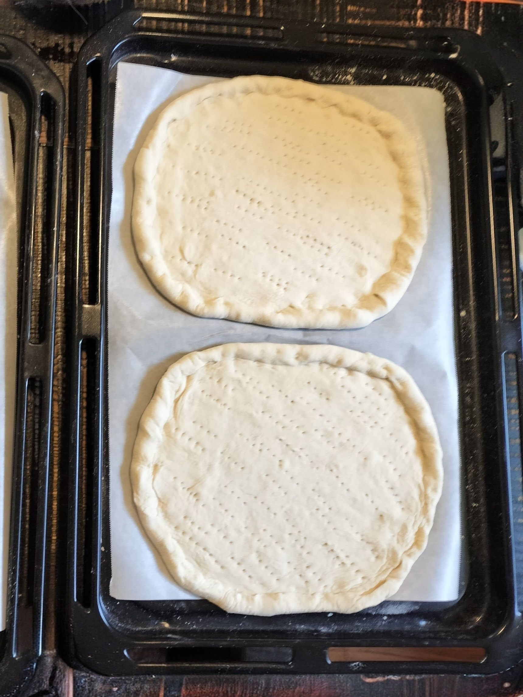 2. 手順1の生地を半分に分ける→麺棒で平らに伸ばす→縁を分厚くする→平な部分にフォーク等で穴を開ける→二次発酵させる