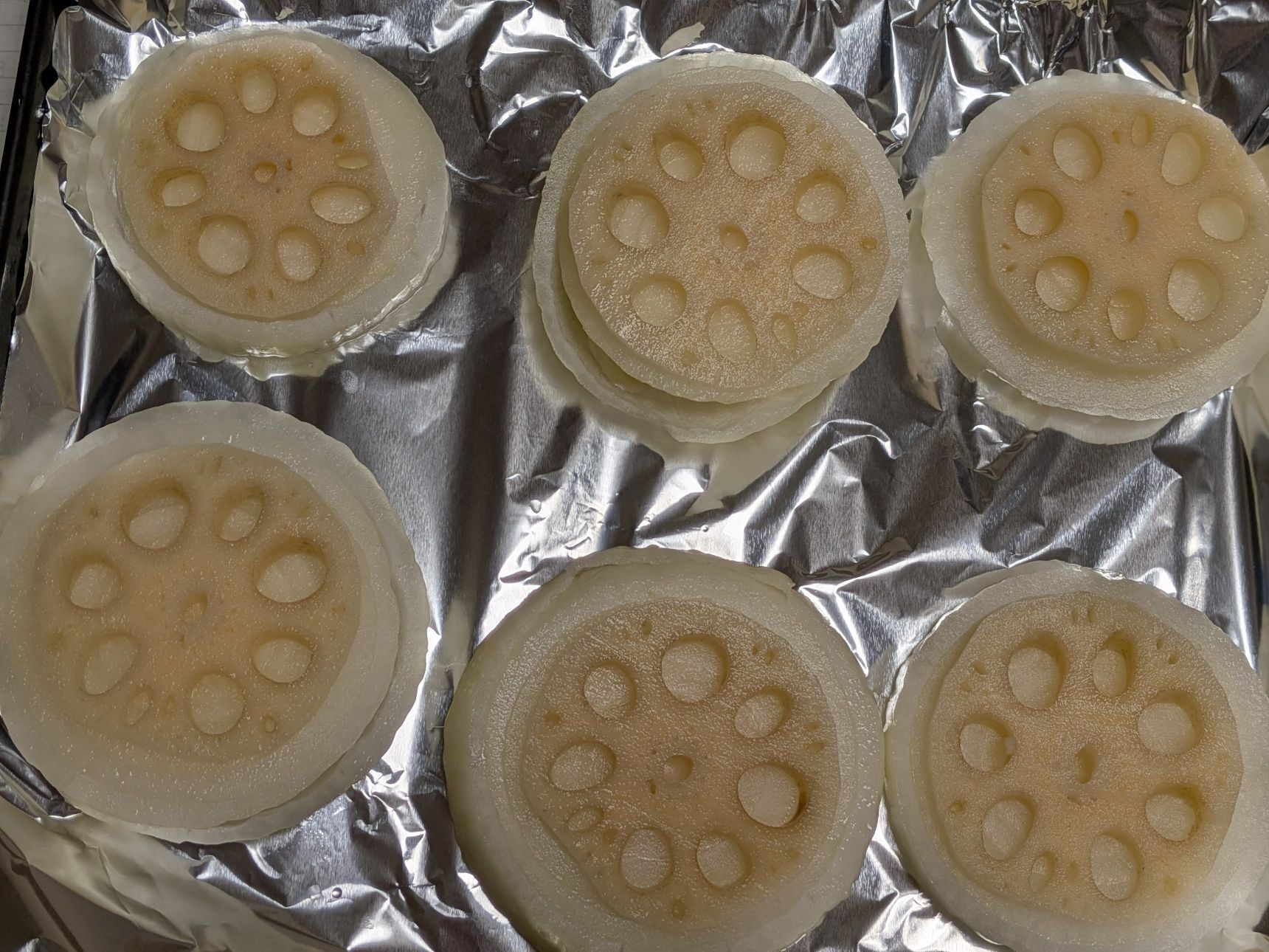 1、新玉ねぎをスライスし、トースターの天板に並べる。れんこんのスライスを上にのせる。塩コショウをかける。