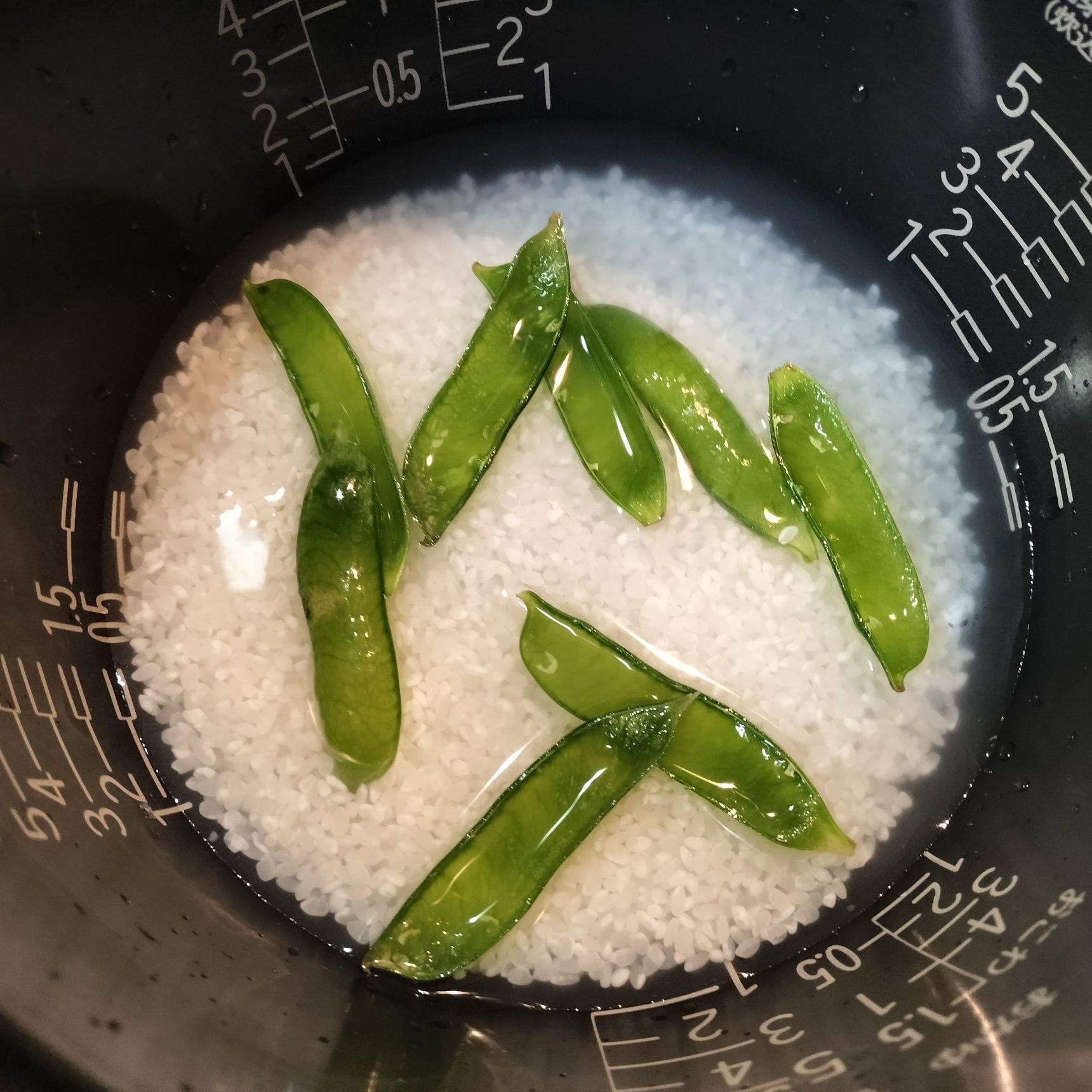 3. お米を研ぐ→お釜に入れて、通常の水の分量を注ぎ入れる→日本酒と少量の天然塩を加えて軽く混ぜる→食べやすい大きさに切ったたけのこと適量のグリンピースのサヤだけを入れる→炊く→サヤを取り出して捨てる→手順2のグリンピースを適量加えて、切るように混ぜる