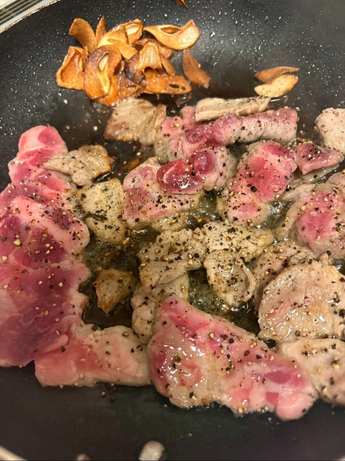 オリーブオイルでスライスしたにんにくと豚肉をカリカリに焼きます。