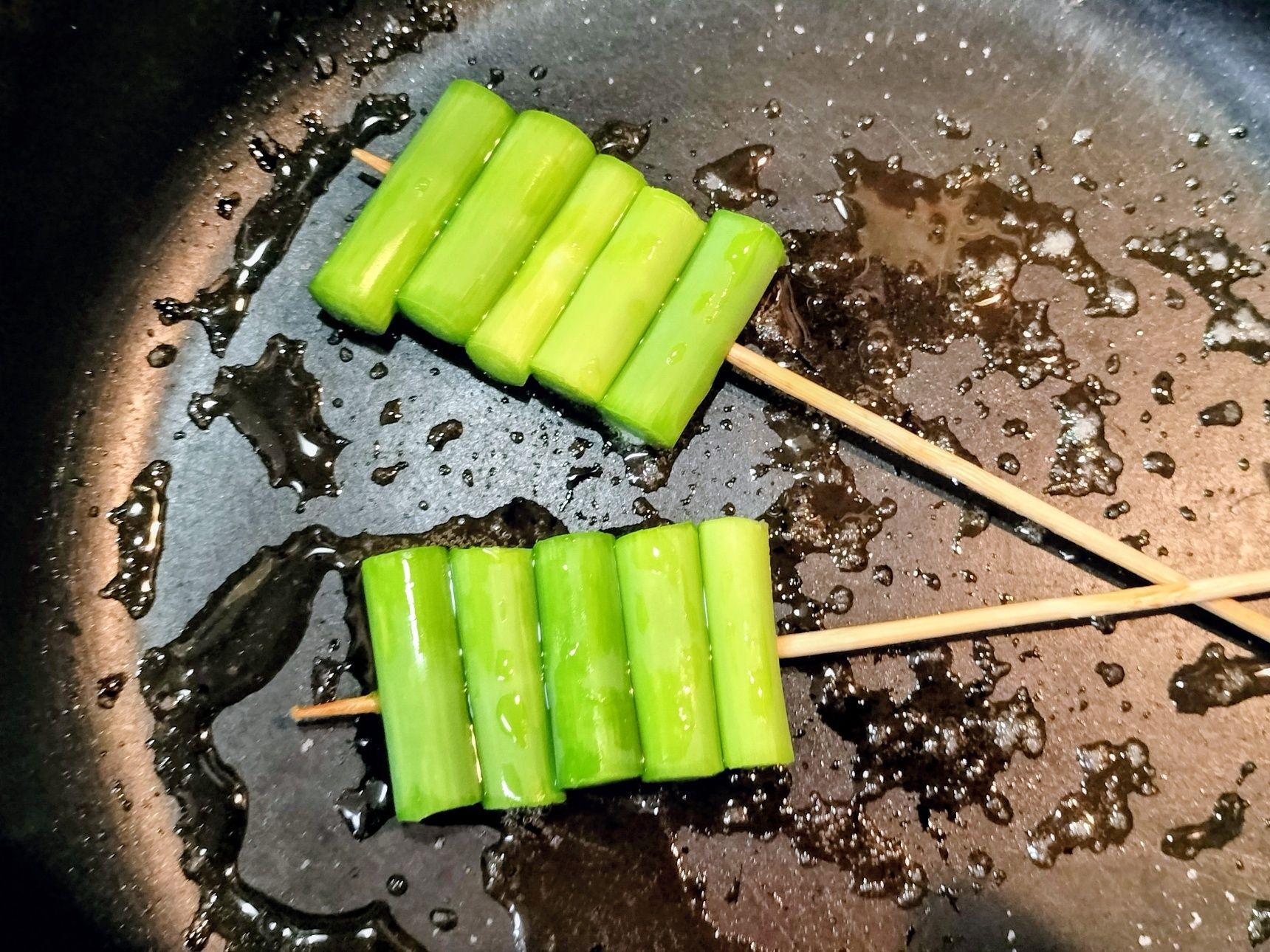 3、フライパンに、ごま油と天然塩を入れる→串に刺したにんにくの芽を入れる→中火で両面をこんがり焼く