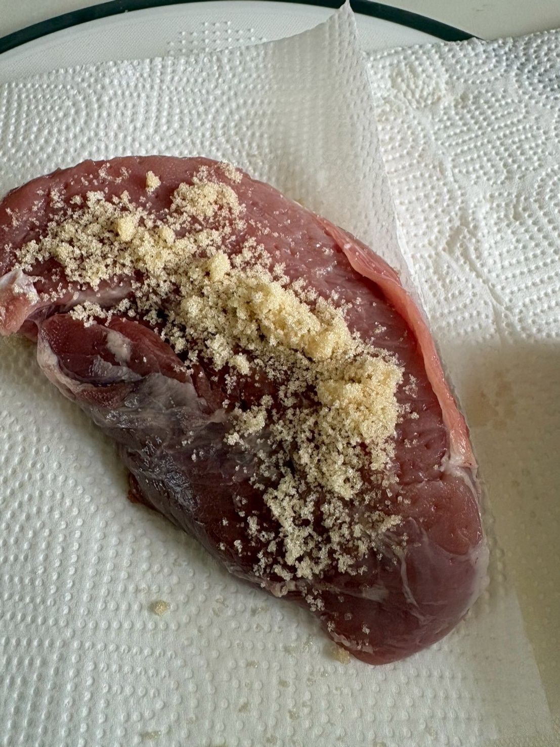 キッチンペーパーの上に肉を乗せて砂糖をまぶします