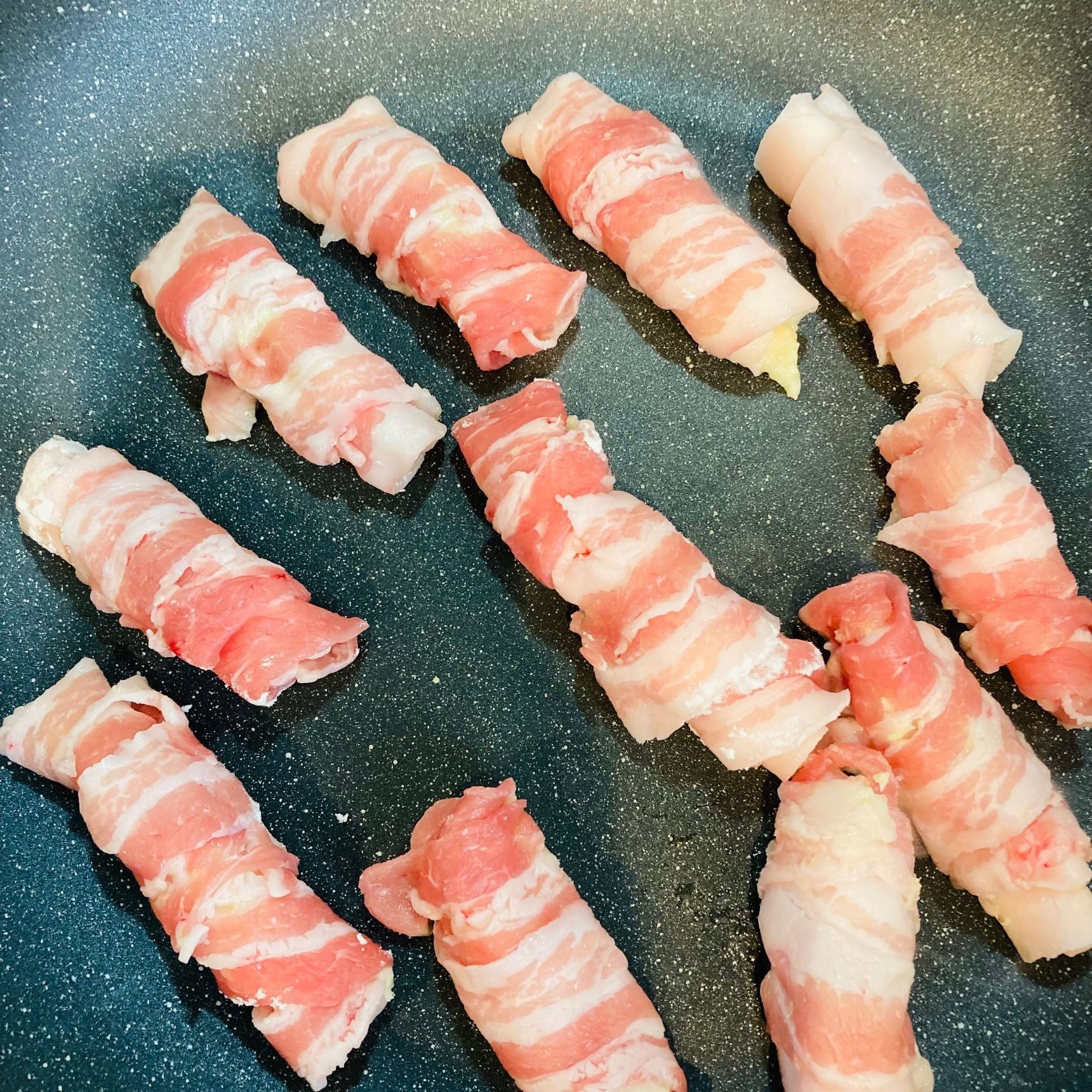 ④ ③の豚肉を端からくるくると巻いて、フライパンに並べ焼きます