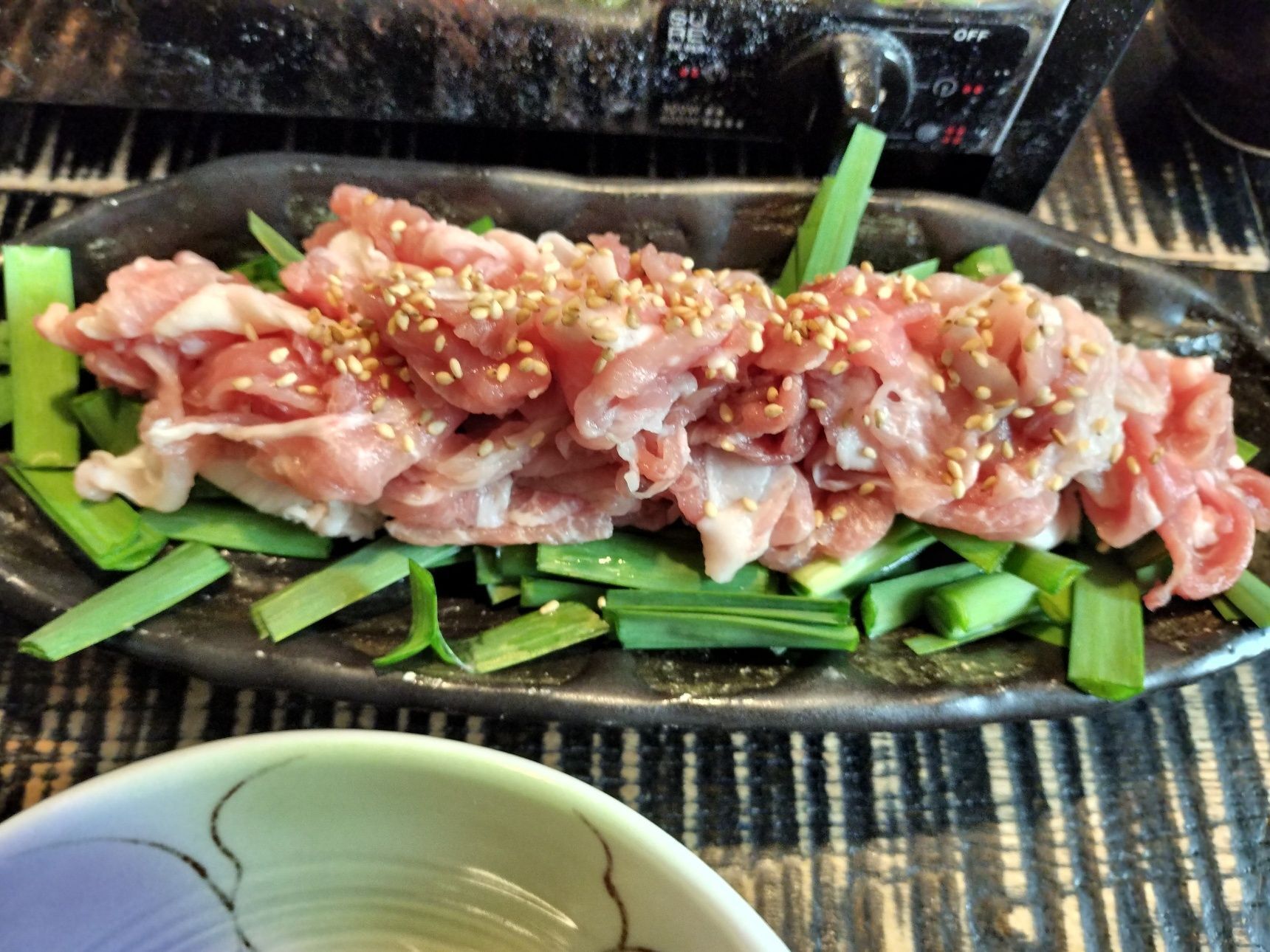 4、銘々皿に、食べやすい長さに切ったニラと豚ロース薄切りを盛りつける→白ごまをふりかける