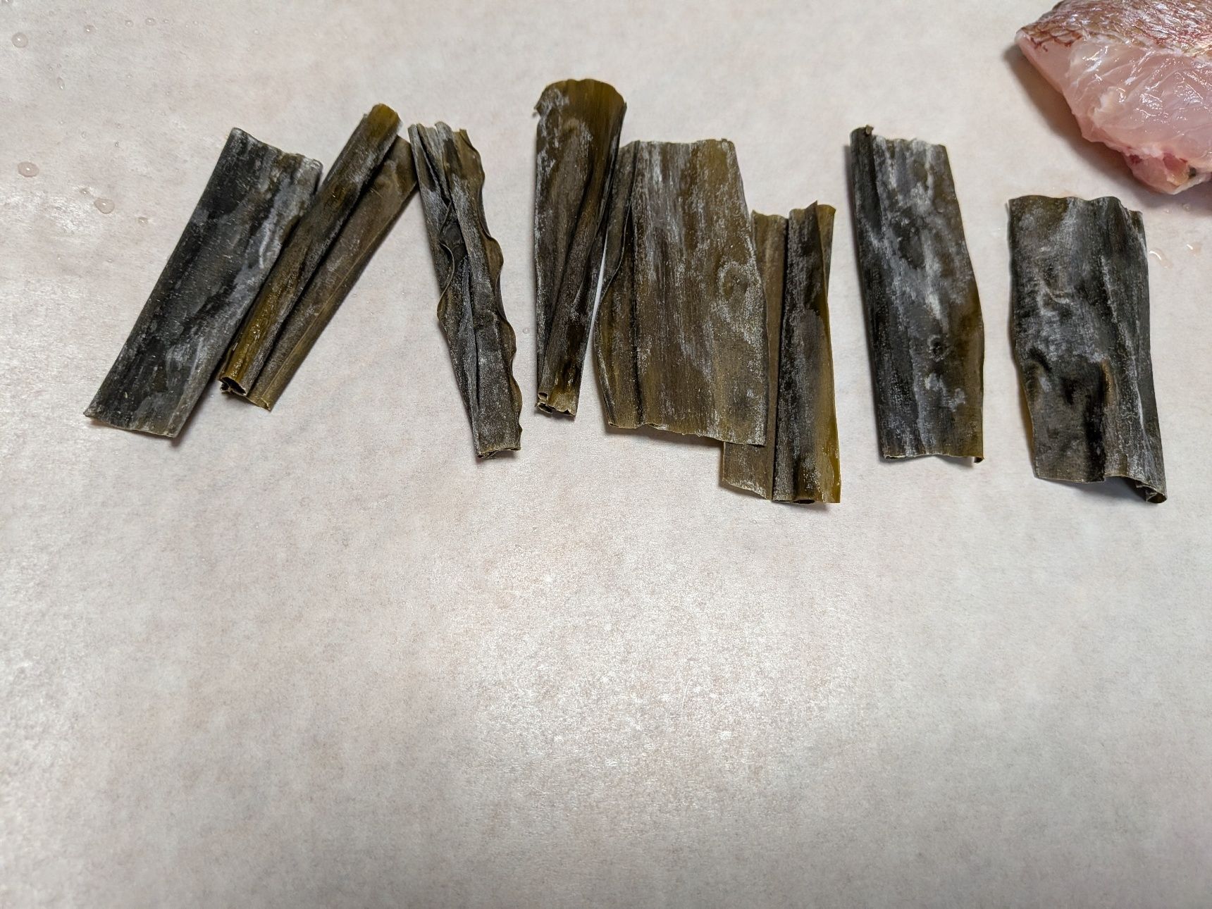 1、クッキングシートを大きめに切り、昆布（あれば）を並べる。