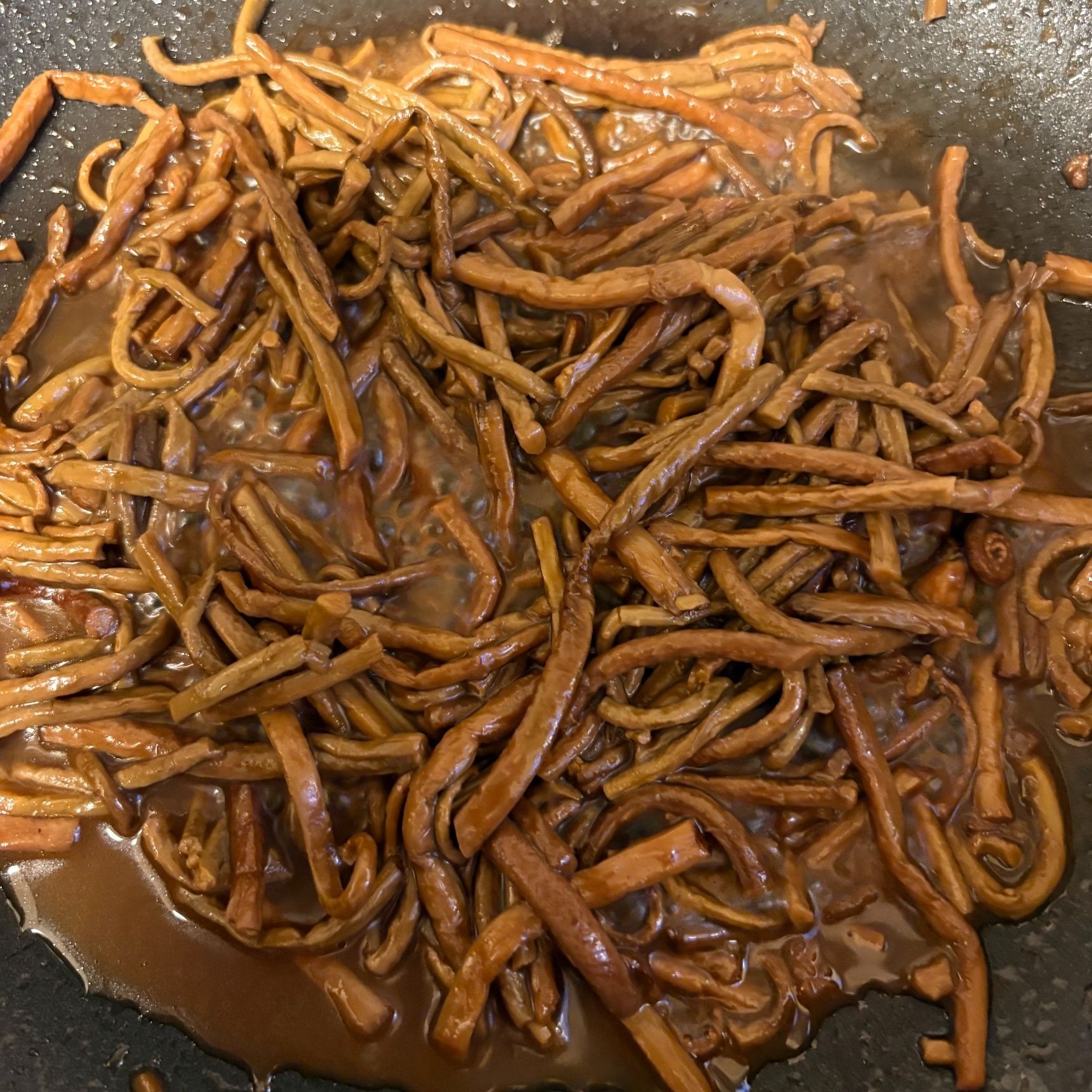 お肉を焼いた後のフライパンにゼンマイを入れタレを少し加えて煮詰めます。