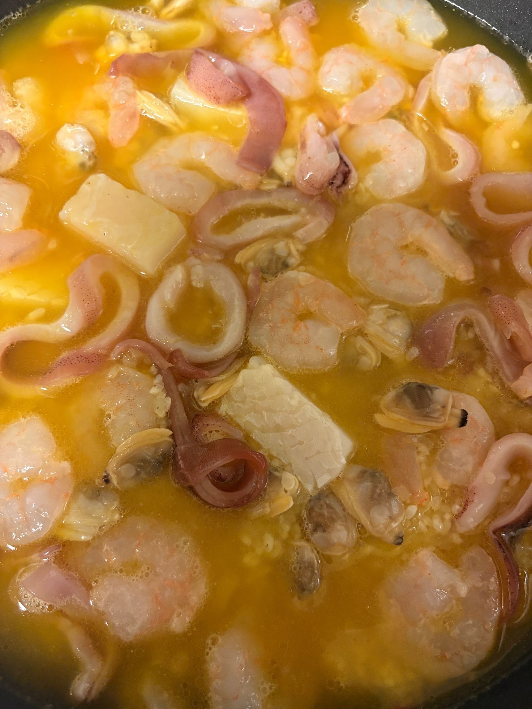 米を平らにした上に魚介類をのせ、パエジャのスープをかけたら蓋をして炊きます。