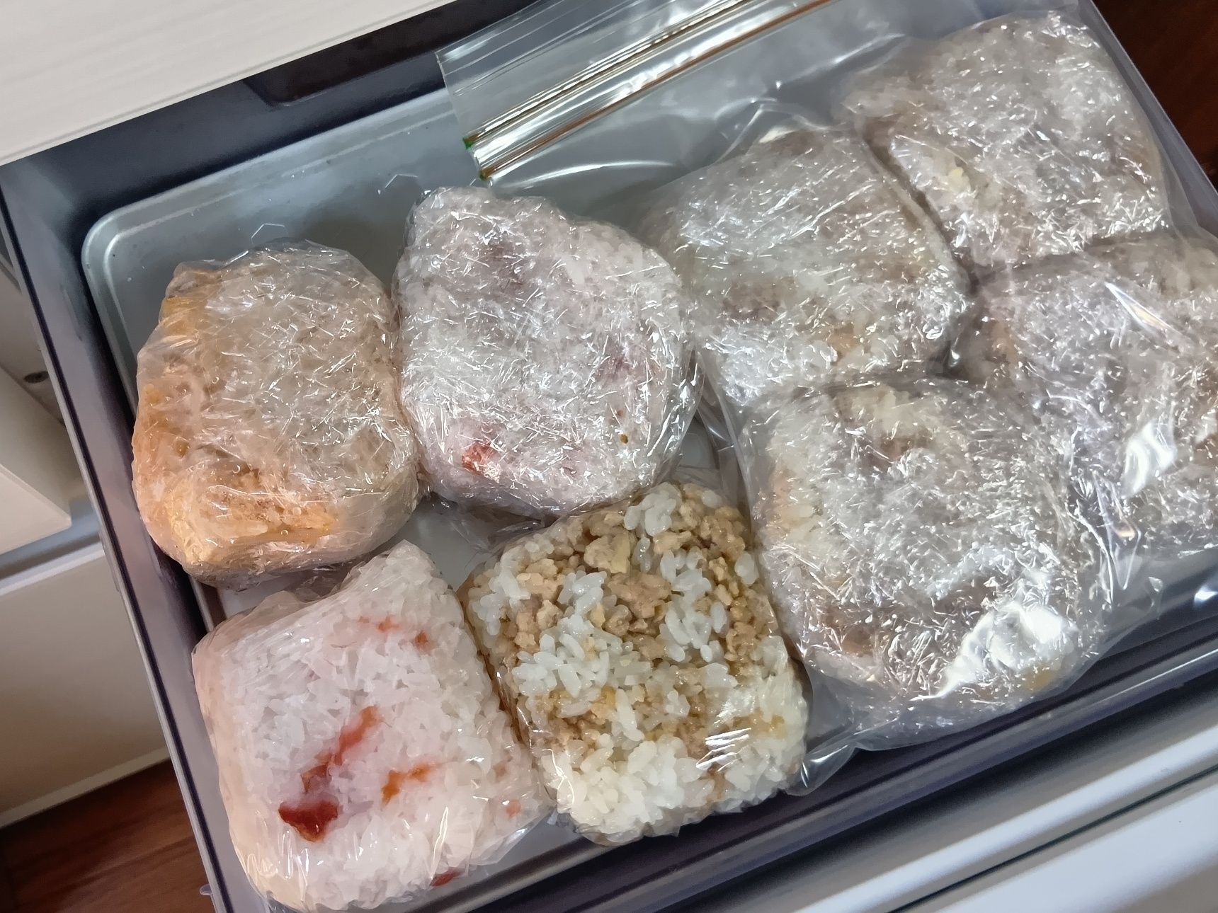 豆腐ケースに合わせておむすびを作ると、大きさを揃えやすく、冷凍庫でもスッキリ保存できる。