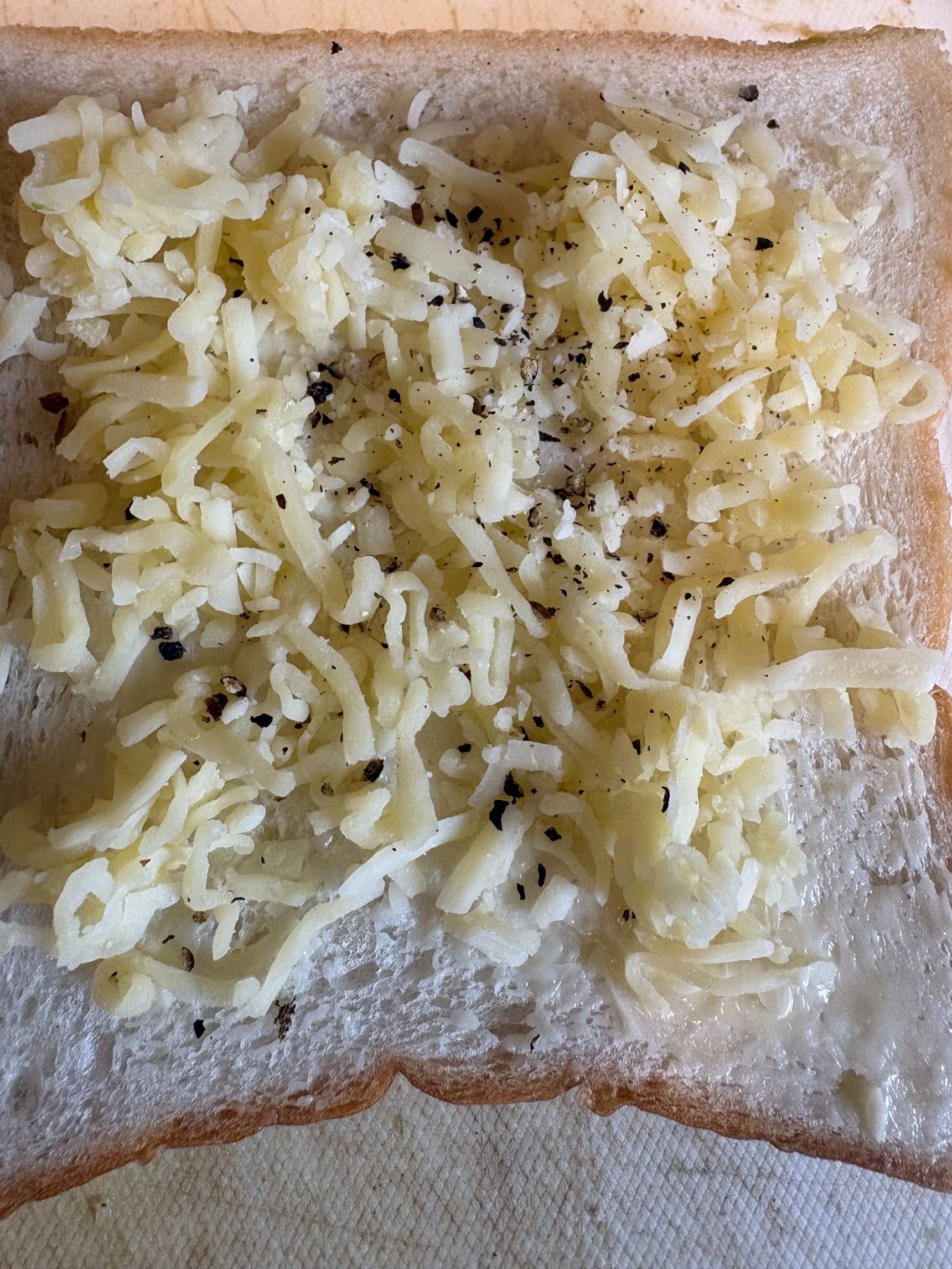 パンにバターを塗り、とろけるチーズをのせたら、ブラックペパーをかけます。