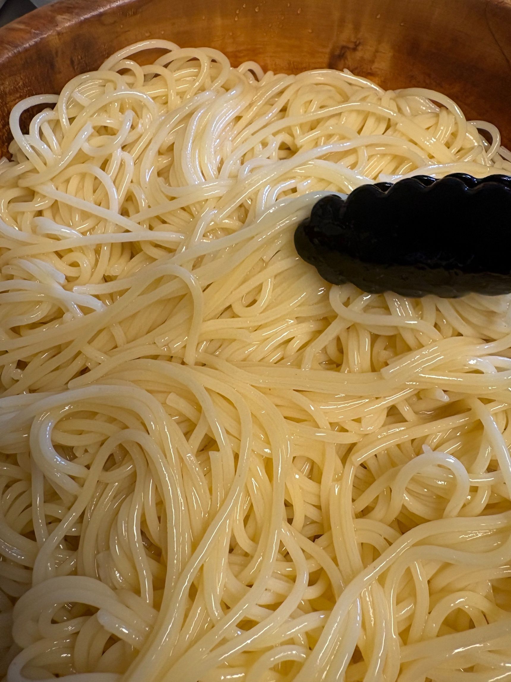 冷めたパスタを大きなボウルに入れて、全体にオリーブオイルをかけます。
