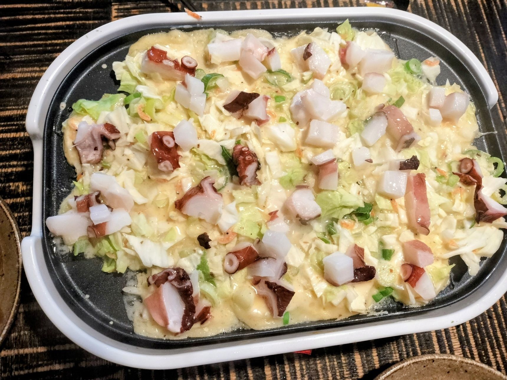 4、たこ焼き器にごま油を塗る→手順3の生地を入れる→たこをのせる→薄く生地をかける→焼く