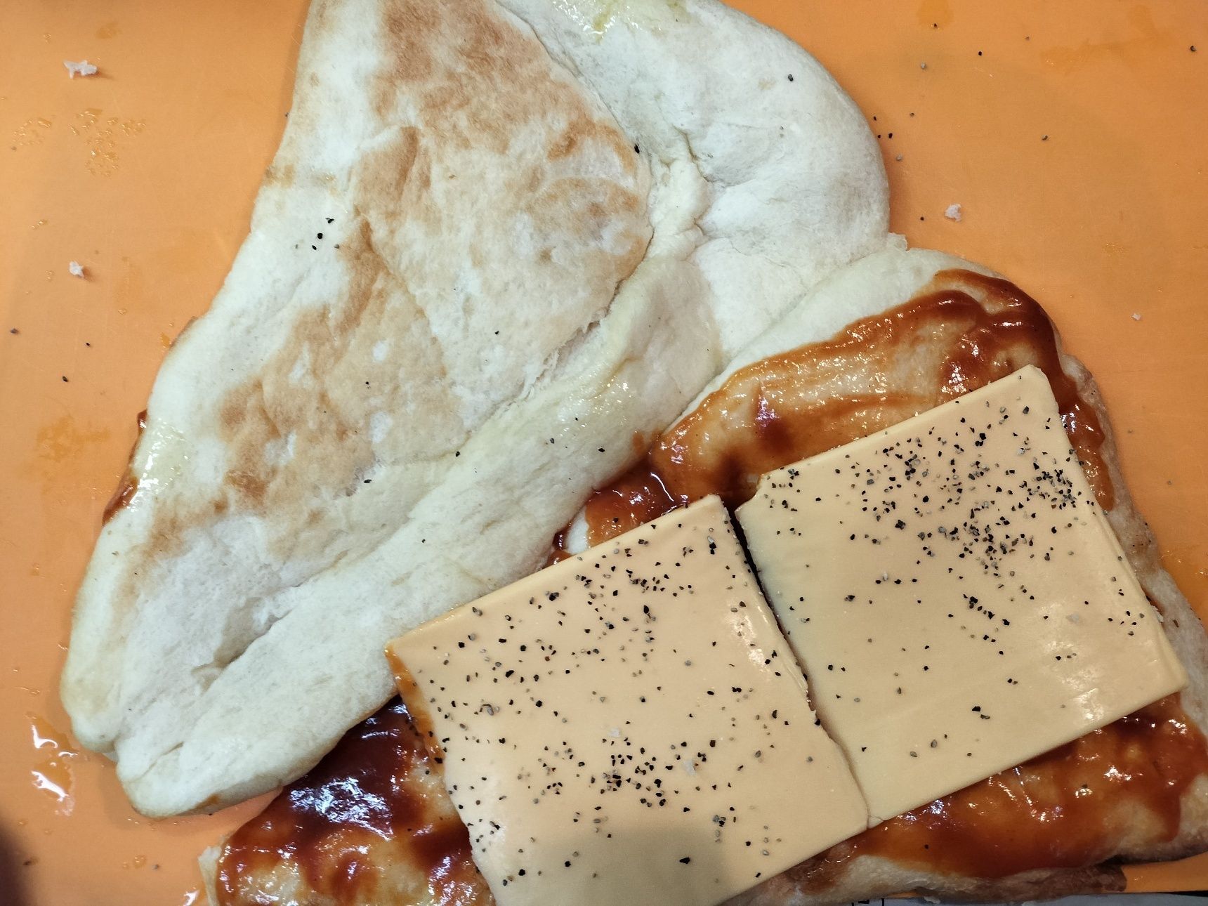 2. ナンに切り込みを入れる→切り口を下にして平らに広げる→焼き色が付いているつるんとした面（片面）に、材料●を塗る→スライスチーズをのせ、粗熱胡椒をふりかける→ナンの繋がっている部分折り曲げ、ナンの形に戻す（切り込みを入れたナンを中表にしてスライスチーズを挟む感じで、焼き色が付いていない中のふかふかな面が外側になります）