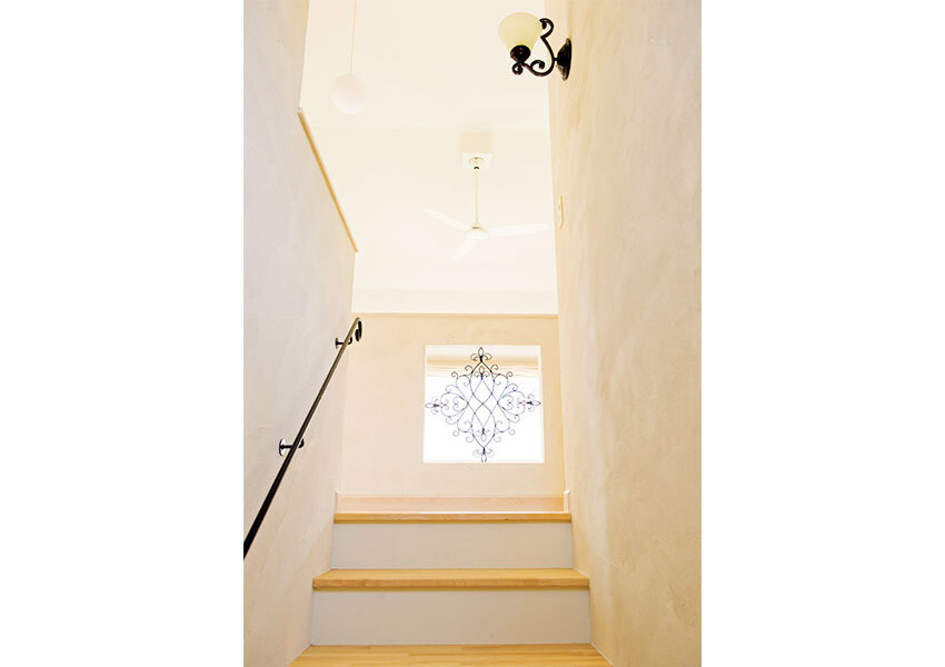 吹き抜けに面した壁にあしらったアイアンパーツがおしゃれな階段